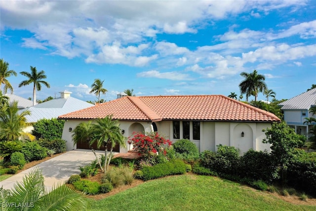 mediterranean / spanish house featuring a garage, a tile roof, driveway, stucco siding, and a front yard