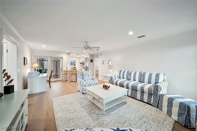 living room featuring ceiling fan, crown molding, and light hardwood / wood-style flooring