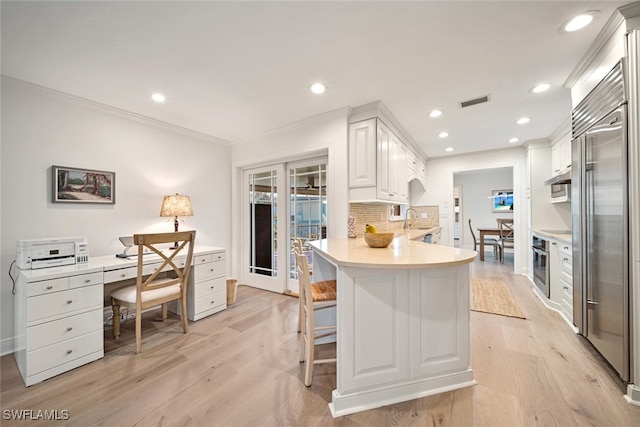 kitchen with white cabinetry, appliances with stainless steel finishes, light hardwood / wood-style floors, and tasteful backsplash