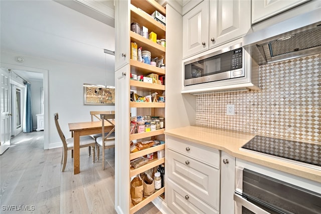 kitchen with stainless steel appliances, tasteful backsplash, ventilation hood, white cabinets, and light wood-type flooring