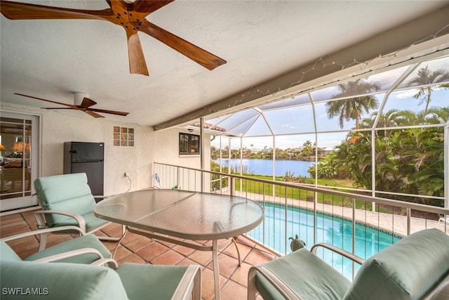 view of swimming pool featuring ceiling fan, glass enclosure, a water view, and a patio area