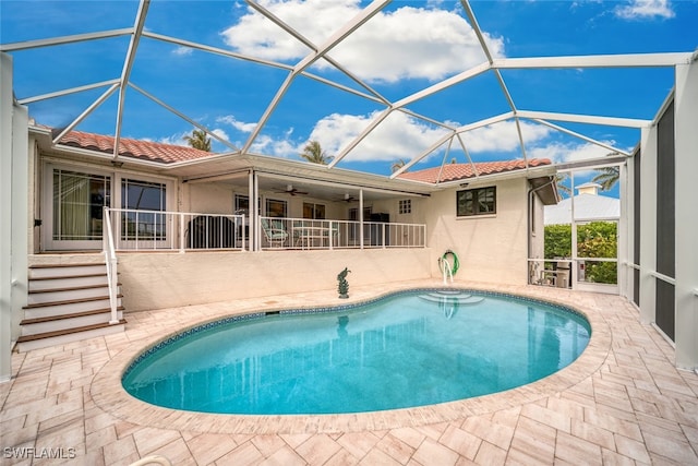 view of swimming pool with ceiling fan, a lanai, and a patio area