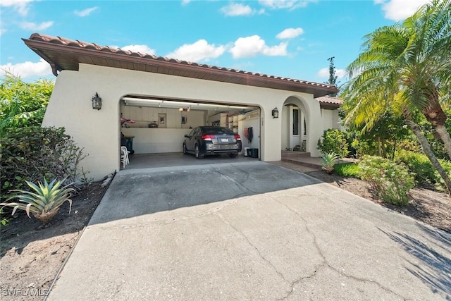 exterior space with concrete driveway, a tile roof, an attached garage, and stucco siding