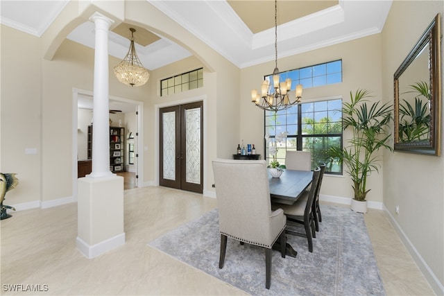 dining room featuring a high ceiling, crown molding, a notable chandelier, decorative columns, and french doors