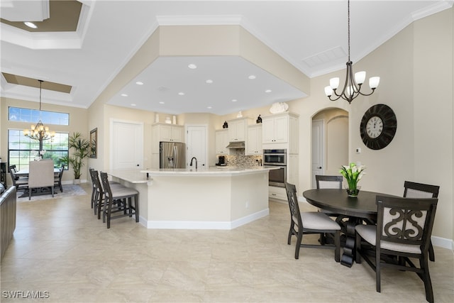 kitchen with a spacious island, stainless steel appliances, hanging light fixtures, and ornamental molding