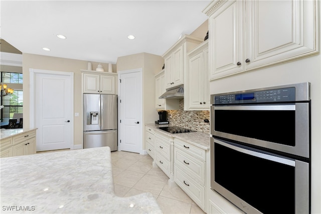 kitchen with appliances with stainless steel finishes, decorative backsplash, light stone counters, and light tile patterned flooring