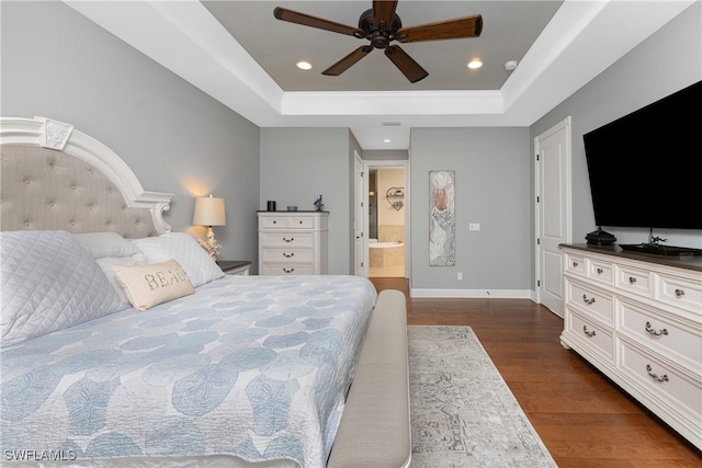 bedroom featuring dark hardwood / wood-style flooring, connected bathroom, ceiling fan, and a raised ceiling