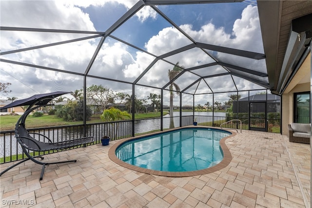 view of pool featuring glass enclosure, a patio area, and a water view