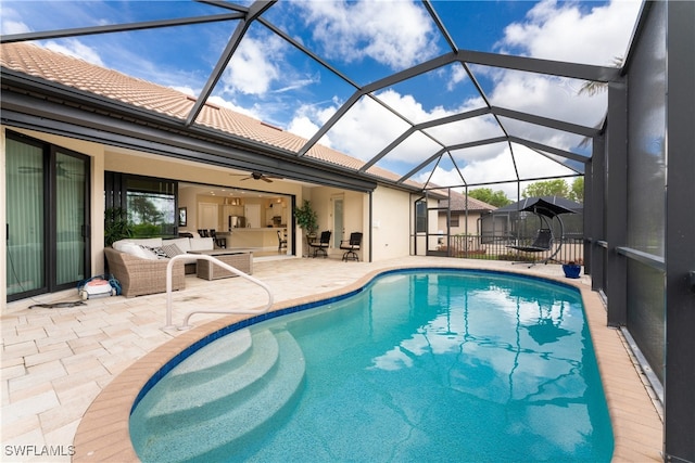 view of pool with glass enclosure, a patio area, an outdoor living space, and ceiling fan