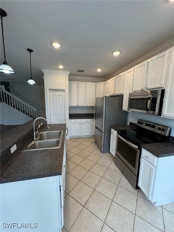 kitchen featuring stainless steel appliances, white cabinetry, sink, light tile patterned floors, and hanging light fixtures