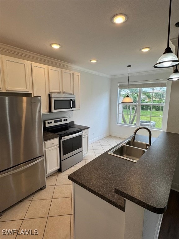 kitchen with appliances with stainless steel finishes, hanging light fixtures, sink, an island with sink, and white cabinets