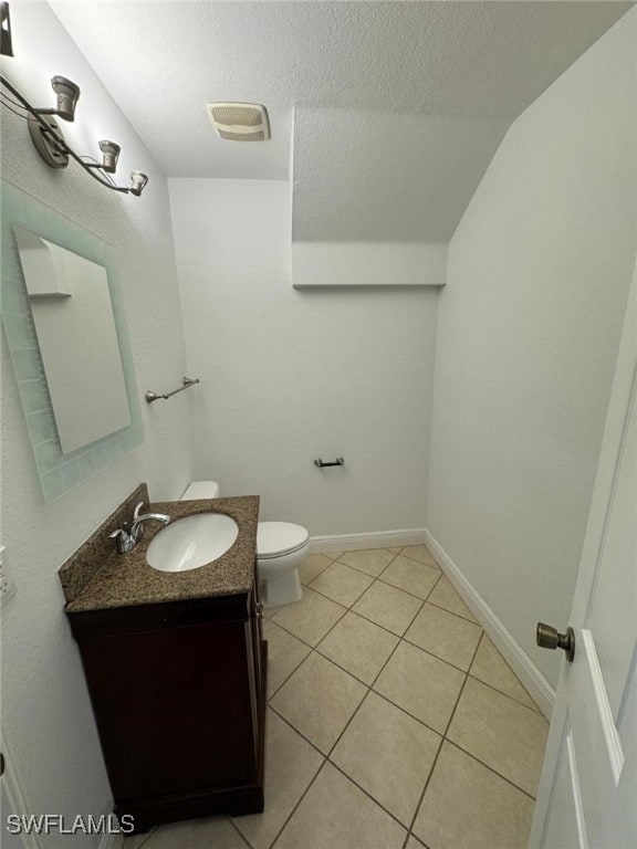 bathroom with tile patterned flooring, a textured ceiling, vanity, toilet, and vaulted ceiling