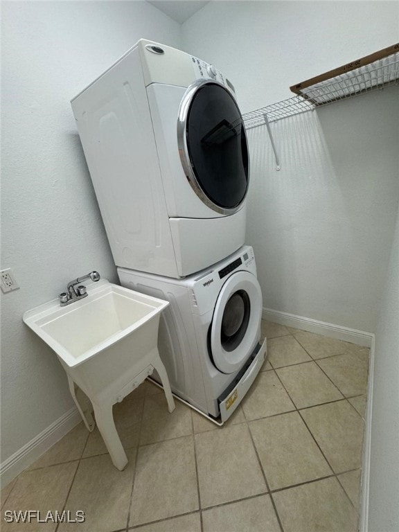 laundry room featuring light tile patterned floors and stacked washer / drying machine