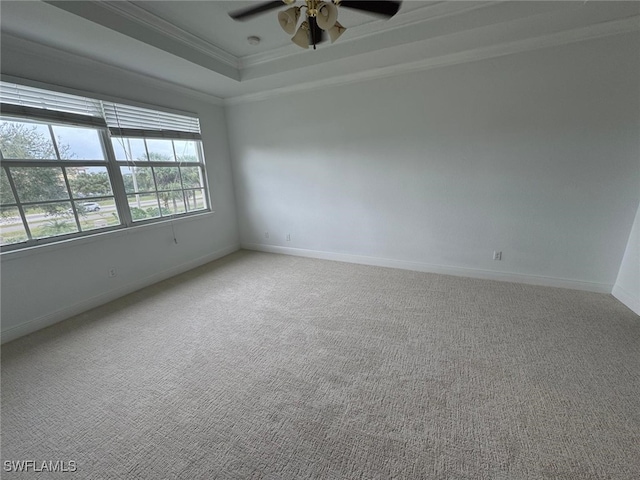 spare room featuring ceiling fan, light colored carpet, ornamental molding, and a raised ceiling