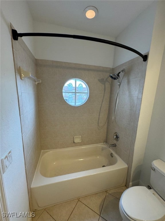 bathroom with tile patterned flooring, tiled shower / bath combo, and toilet