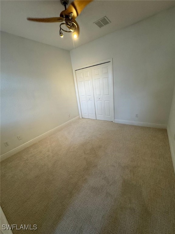 unfurnished bedroom with carpet, ceiling fan, and a closet