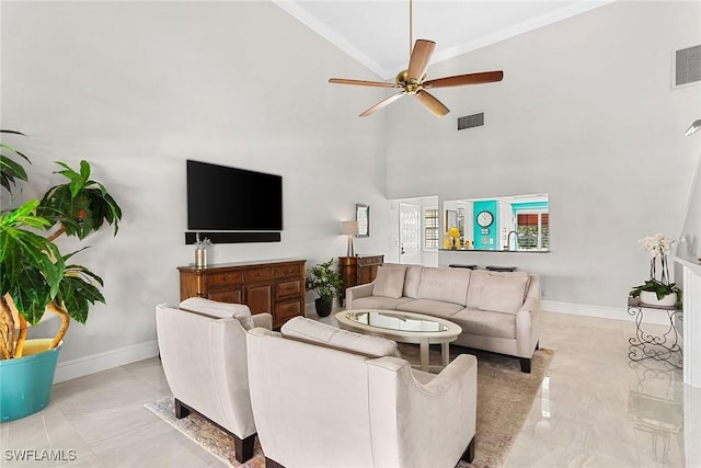 living room featuring ceiling fan, ornamental molding, and a high ceiling