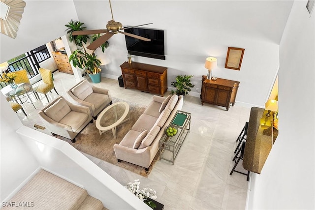 living room featuring ceiling fan and a high ceiling