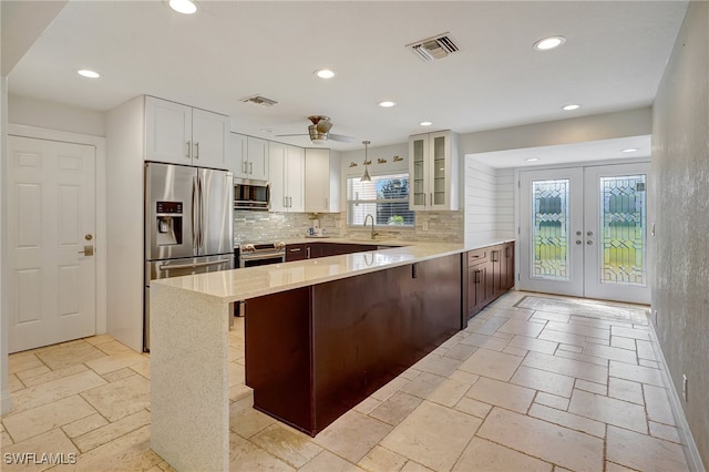 kitchen featuring french doors, stainless steel appliances, decorative light fixtures, and a healthy amount of sunlight