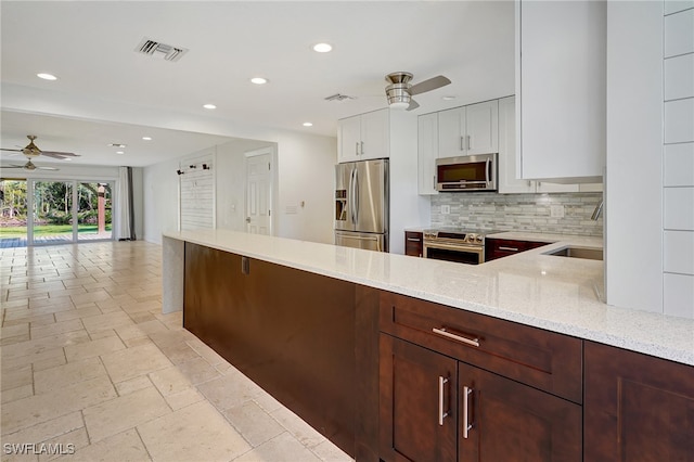 kitchen with light stone countertops, sink, stainless steel appliances, decorative backsplash, and white cabinets