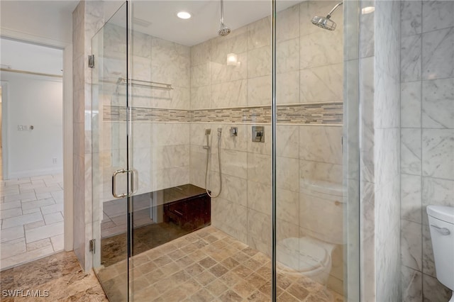 bathroom featuring toilet and a shower with shower door