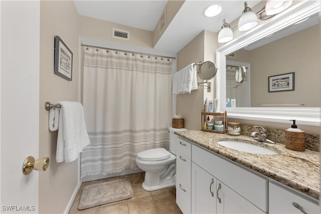 bathroom with toilet, vanity, and tile patterned flooring