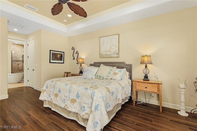 bedroom with a tray ceiling, ensuite bath, and ceiling fan