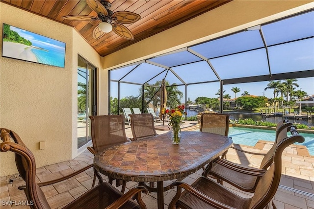 view of patio with a water view, ceiling fan, and a lanai