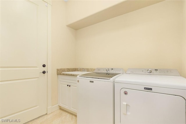 laundry area featuring separate washer and dryer, sink, light tile patterned floors, and cabinets