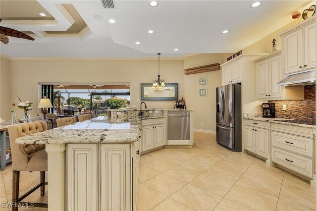 kitchen featuring hanging light fixtures, stainless steel appliances, a kitchen breakfast bar, crown molding, and cream cabinets