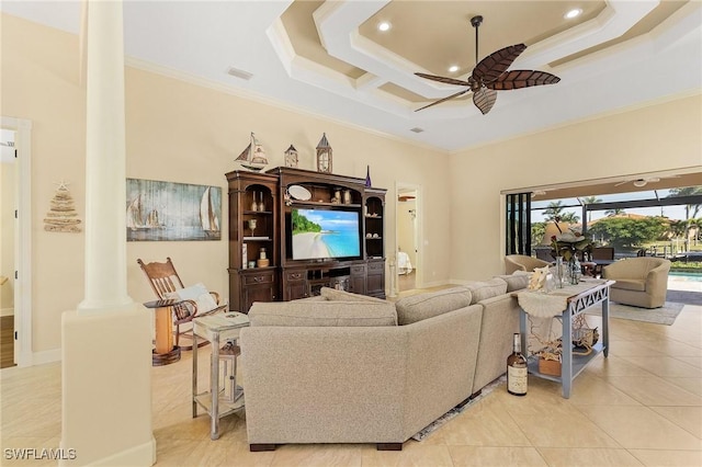 tiled living room featuring ornate columns, a tray ceiling, ceiling fan, crown molding, and a high ceiling