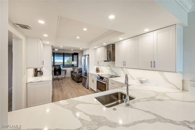 kitchen with white cabinetry, light stone countertops, light hardwood / wood-style floors, and stainless steel appliances