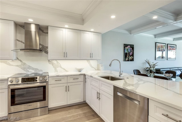 kitchen with white cabinetry, sink, appliances with stainless steel finishes, light hardwood / wood-style flooring, and wall chimney range hood