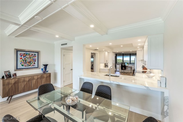 dining area with ornamental molding, sink, light hardwood / wood-style floors, and beam ceiling