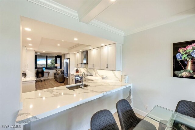 kitchen featuring white cabinetry, sink, kitchen peninsula, a kitchen breakfast bar, and light wood-type flooring