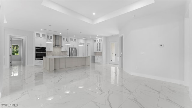 kitchen with stainless steel appliances, a large island, white cabinetry, wall chimney range hood, and pendant lighting