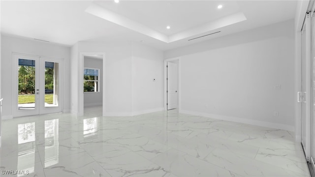 unfurnished room featuring french doors and a raised ceiling