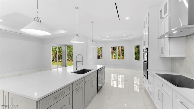 kitchen with stainless steel appliances, white cabinets, wall chimney exhaust hood, hanging light fixtures, and a spacious island