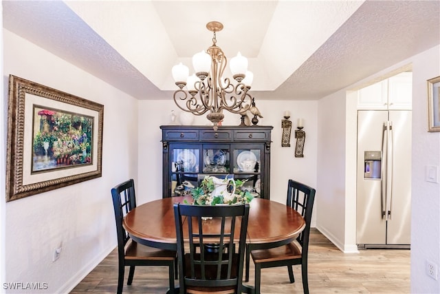 dining area featuring a textured ceiling, light wood-type flooring, and a notable chandelier