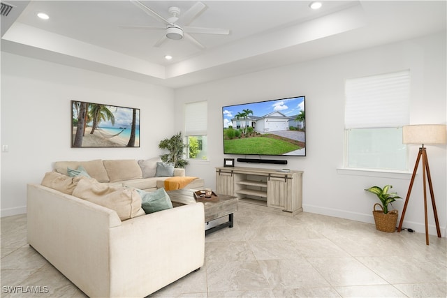 living room with ceiling fan and a tray ceiling