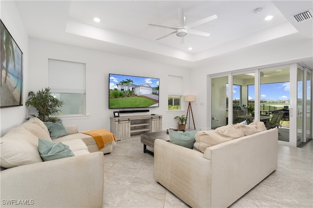 living room featuring ceiling fan and a raised ceiling