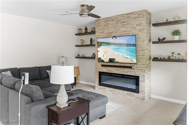 living room with a stone fireplace, ceiling fan, and light tile patterned flooring