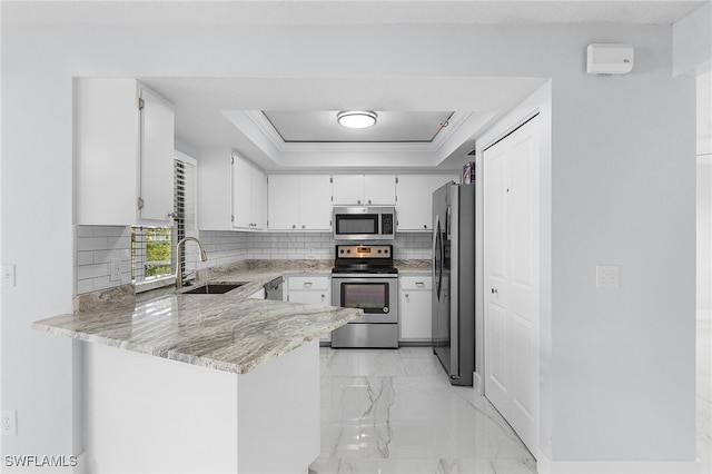 kitchen with white cabinetry, appliances with stainless steel finishes, light stone countertops, sink, and kitchen peninsula