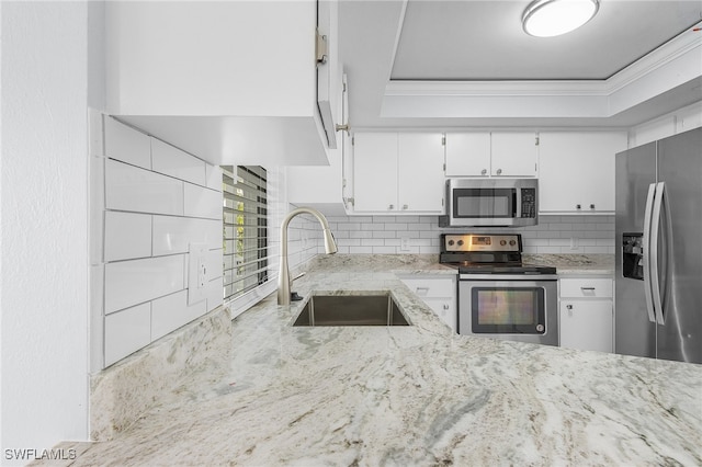 kitchen with white cabinetry, stainless steel appliances, sink, and a tray ceiling