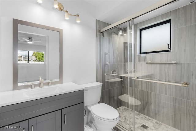 bathroom featuring toilet, vanity, ceiling fan, and a shower with shower door