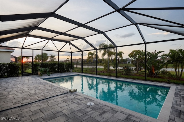 pool at dusk with glass enclosure and a patio area