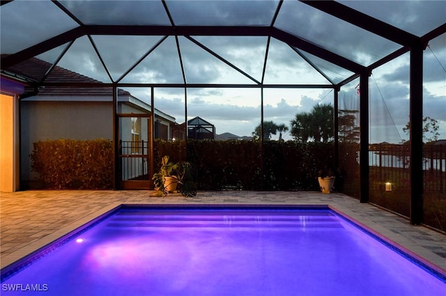 view of swimming pool featuring glass enclosure and a patio area