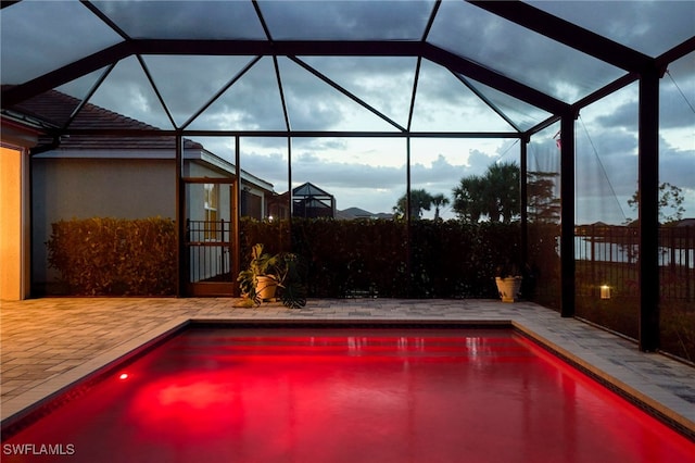 view of swimming pool with glass enclosure and a patio