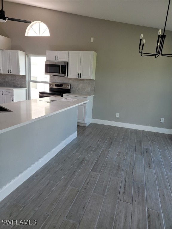 kitchen featuring white cabinets, light hardwood / wood-style flooring, backsplash, pendant lighting, and appliances with stainless steel finishes