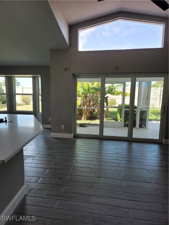 unfurnished living room with high vaulted ceiling and dark wood-type flooring